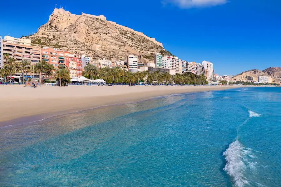 Playa del Postiguet in Alicante with golden sand, turquoise waters and Santa Bárbara Castle in the background