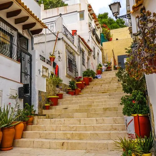 Whitewashed houses and flowerpots along the steps of Barrio de Santa Cruz in Alicante