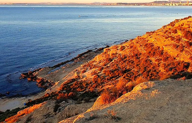 Panoramic view of Cabo de la Huerta in Alicante at sunset, with golden cliffs and the Mediterranean Sea in the background