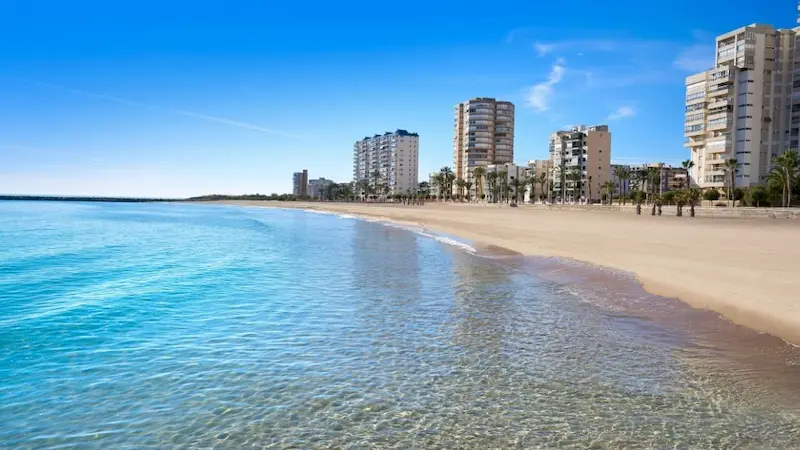 Platja del Carrer de la Mar in El Campello, Alicante, with golden sand, turquoise waters, and beachfront promenade with buildings