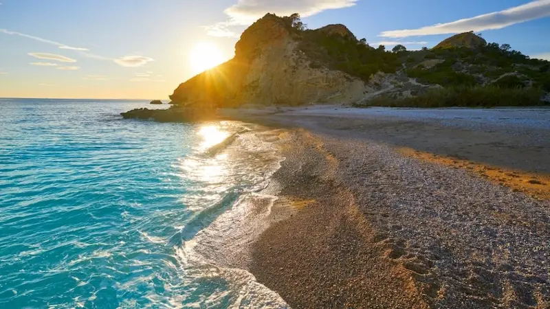 Paradise Beach in Villajoyosa, Alicante, with turquoise waters, golden cliffs, and sunset view over the Mediterranean