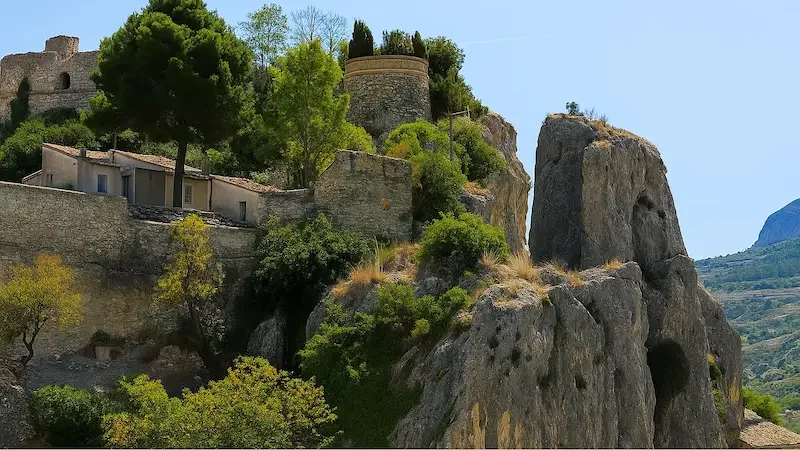 View of Mirador de la Muralla in Guadalest, showing the ancient stone walls, rocky cliffs, and lush greenery overlooking the valley on the Costa Blanca